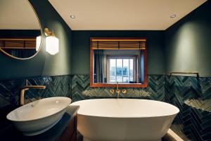 a bathroom with a tub and a sink and a mirror at Villa Viva - ein Haus das Brunnen baut in Hamburg