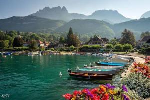 um grupo de barcos em um lago com montanhas ao fundo em le marmoton em Thônes