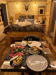 una mesa con comida y bebida y una cama en Les Écrins du Val de Mouthe, JURA, 