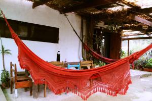 eine rote Hängematte in einem Zimmer mit einem Tisch in der Unterkunft Arcadio Hostel Punta del Diablo in Punta Del Diablo