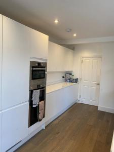 een keuken met witte kasten en een oven bij Stunning 4BD House wLarge Garden - Finsbury Park! in Londen