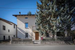 ein weißes Haus mit einem Zaun und einem Baum in der Unterkunft B&B Cà Selvetta in Forcola