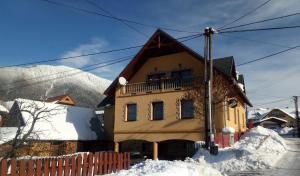 żółty dom z balkonem w śniegu w obiekcie Penzión Serafín w Rużomberku