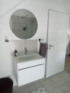 a white bathroom with a sink and a mirror at Spacious loft in Paternoster