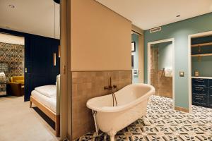 a bathroom with a bath tub and a bedroom at Villa Viva - ein Haus das Brunnen baut in Hamburg