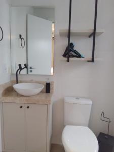 a bathroom with a white toilet and a sink at Apartamento Sol e Mar in Itapema