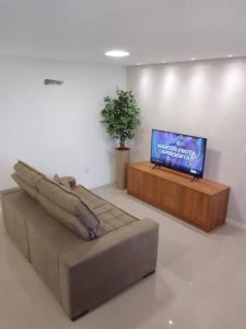 a living room with a couch and a flat screen tv at Apartamento Sol e Mar in Itapema