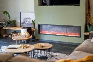 a living room with a fireplace and two tables at Luxe bosvilla De Paradijsvogel in Rijs