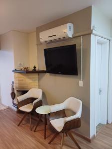 sala de estar con 2 sillas y TV de pantalla plana en Ap dos primos, en Capão da Canoa