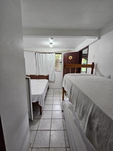 um pequeno quarto com 2 camas e uma janela em Pousada Recanto das Ondas em Garopaba