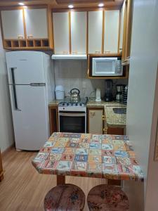 uma pequena cozinha com uma mesa e um frigorífico em Ap dos primos em Capão da Canoa