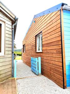 un edificio de madera con una valla azul al lado en La Maison Bleue, en Urville-Nacqueville