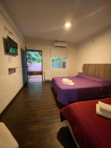 a room with two beds with purple sheets and a window at Hotel Cristobal de Colón in Colón