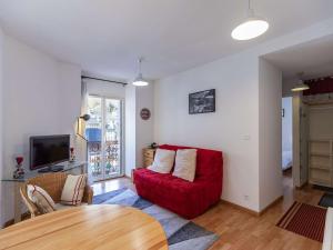 a living room with a red couch and a table at Spacieux T2 centre ville avec WIFI et équipements sportifs - FR-1-401-274 in Cauterets +3 photos