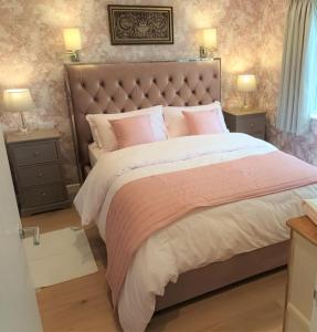 a bedroom with a large bed with pink pillows at Paradise in the Oxfordshire Cotswolds in Epwell