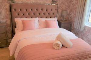duże łóżko z różową pościelą i poduszkami w obiekcie Paradise in the Oxfordshire Cotswolds w mieście Epwell