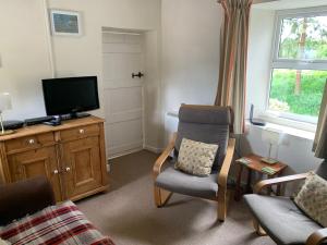 a living room with a tv and a chair at Garbutt Cottage in Langthwaite