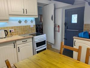 a kitchen with white cabinets and a blue door at Garbutt Cottage in Langthwaite