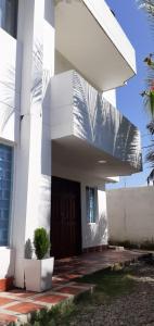 un bâtiment blanc avec une porte et un palmier dans l'établissement Casa hostal Rochymar, 