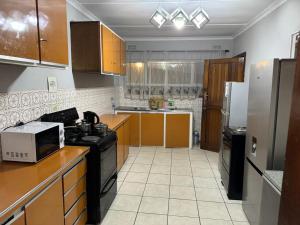 una cocina con estufa y refrigerador en Lindokuhle Holiday Accommodation, en Durban