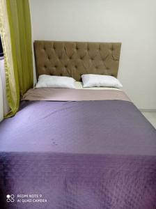 a bed with a purple comforter and two pillows at casa com piscina, 03 quartos, ótima localização! in Bonito
