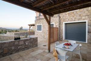 a patio with a table and chairs and a stone wall at Lampetos Houses Molyvos in Mythimna