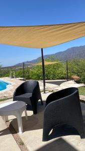 a patio with chairs and a table and a pool at QHAWANA CABAÑAS & SUITES in La Rioja