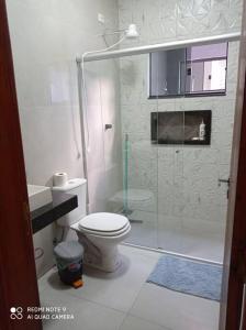 a bathroom with a toilet and a glass shower at casa com piscina, 03 quartos, ótima localização! in Bonito