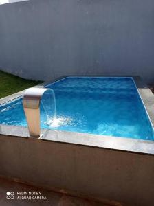 ein blauer Pool mit einem Springbrunnen in der Unterkunft casa com piscina, 03 quartos, ótima localização! in Bonito