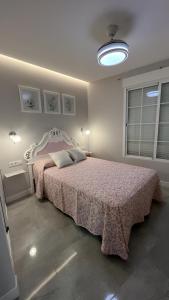 sypialnia z łóżkiem z różową narzutą w obiekcie Aptos Estación Norte y Sur FAMORCAS w mieście Almodóvar del Río