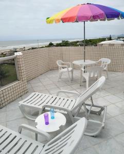 eine Terrasse mit Tischen, Stühlen und einem Sonnenschirm in der Unterkunft Apartamento de cobertura na beira mar e de frente para o mar. Vista maravilhosa. in Pontal do Paraná