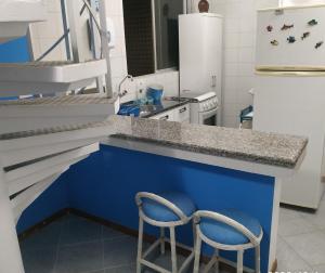 eine Küche mit einer blauen Theke und 2 Stühlen in der Unterkunft Apartamento de cobertura na beira mar e de frente para o mar. Vista maravilhosa. in Pontal do Paraná