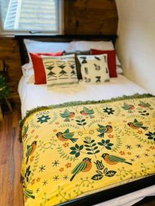a bed with a yellow blanket with birds on it at Clyde Croft - (Luxury Cabin) in Portpatrick
