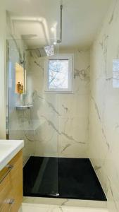 La salle de bains est pourvue d'une douche avec une porte en verre. dans l'établissement Bel appartement proche de Paris, à Villemomble