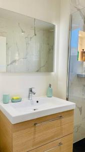 La salle de bains est pourvue d'un lavabo blanc et d'un miroir. dans l'établissement Bel appartement proche de Paris, à Villemomble