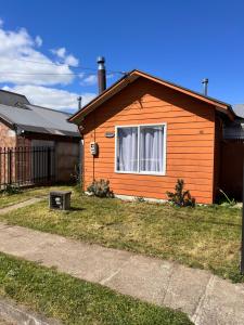 an orange house with a window in a yard at Casa a 10 minutos del centro Osorno in Osorno