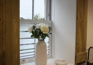 um vaso branco com flores no peitoril da janela em Vintage Beach House em Lower Largo