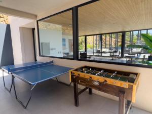 - une table de ping-pong bleue dans une pièce dotée de fenêtres dans l'établissement Confortable y Centrico Depto Papudo, à Papudo