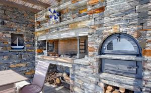 an outdoor kitchen with a stone wall with a fireplace at Mavrabeli Sunset Retreat in Ioulida