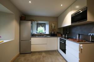 a kitchen with white cabinets and a stainless steel refrigerator at 300-year-old Farmhouse Chalet in Servoz +22 photos