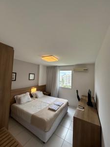 1 dormitorio con cama, escritorio y ventana en Apartamentos no Verano Stay, en Río de Janeiro