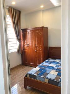 a bedroom with a bed and a cabinet and a window at Flat near SGN Ho Chi Minh City Airport in Ho Chi Minh City