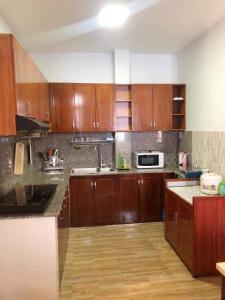 a kitchen with wooden cabinets and a microwave at Flat near SGN Ho Chi Minh City Airport in Ho Chi Minh City