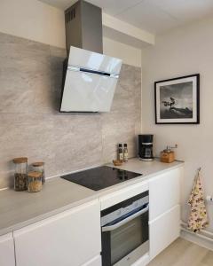 een keuken met witte kasten en een fornuis met oven bij Moderne villalejlighed på 110 kvm + stor terrasse in Viby
