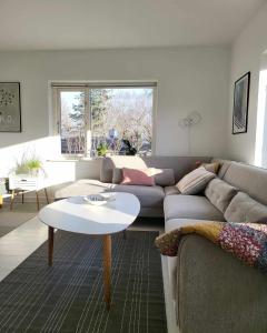Moderne villalejlighed på 110 kvm + stor terrasse في Viby: غرفة معيشة مع أريكة وطاولة