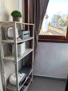 a room with a shelf with a tv and a window at APARTAMENTO PLAYA URB PRIVADA 2 Habitaciones in Valencia