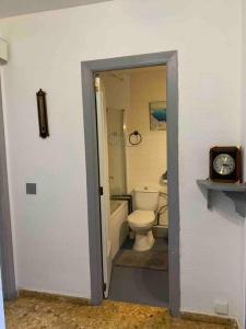 a bathroom with a toilet and a sink and a clock at APARTAMENTO PLAYA URB PRIVADA 2 Habitaciones in Valencia