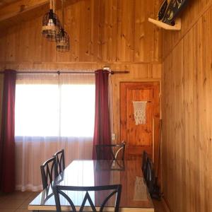 een eetkamer met een tafel en stoelen en een raam bij Comoda Cabaña en Pichilemu in Pichilemu