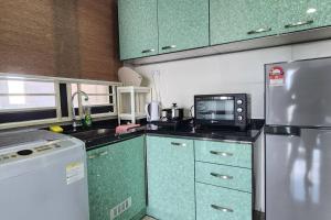a kitchen with green cabinets and a refrigerator at JC Sky Riverfront 'Nebula' in Kota Bharu
