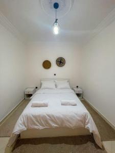 Tamraght OuzdarにあるMoroccan Charm: Cozy Apartment with PrivateTerraceの白いベッドと2つのナイトスタンドを備えた寝室